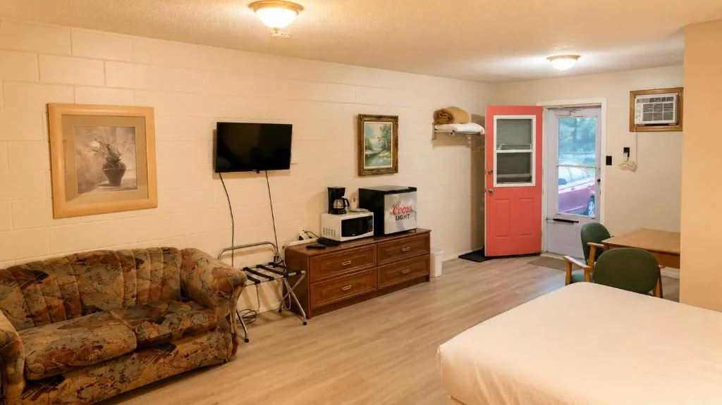 Wide guest room with couch, television, table and warm wood finishes